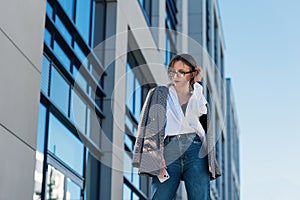 Successful beautiful business woman in suit with document walking to the meeting near modern office building.