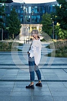 Successful beautiful business woman in suit with document walking to the meeting near modern office building.