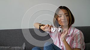 Successful beautiful woman sitting on couch holds glasses in his hands and smiles thoughtfully.