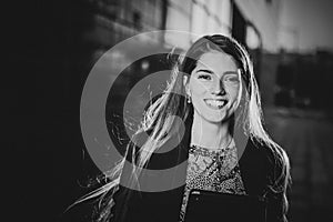 Successful beautiful young business woman is smiling on the background of buildings and holding a tablet computer.