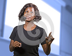 Successful black African American entrepreneur woman with headset speaking in auditorium at corporate training event or seminar