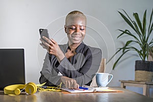 Successful black afro American business woman working at modern office with mobile phone writing notes on notepad