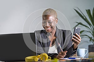 Successful black afro American business woman working at modern office with mobile phone writing notes on notepad