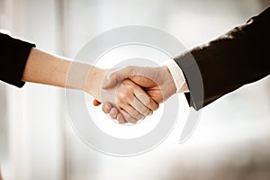 Successful business concept. Young businesswoman and businessman shake hands closeup after signing partnership
