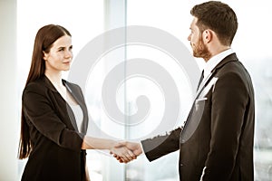 Successful business concept. Young businesswoman and businessman shake hands after signing partnership cooperation