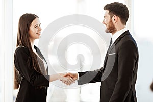 Successful business concept. Young businesswoman and businessman shake hands after signing partnership cooperation