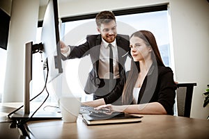 Successful business concept. Young businesswoman sits at the office table busy working on computer. Happy smiling