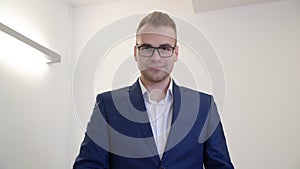 Successful business man in eyeglasses and blue suit looking wrist clock in office