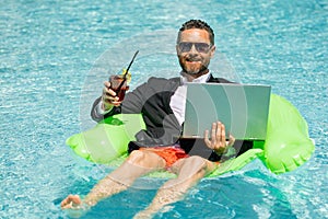 Successful business man floating in suit in pool water. Summer vacations and travel concept. Funny business man drink