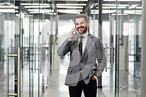 Successful business man have telephone conversation while standing in empty office corridor. Male professional banker in
