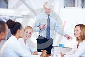 Successful business man presenting to his team. Portrait of successful senior business man presenting to his colleagues.