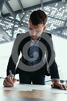 Successful business man signing documents in a modern office