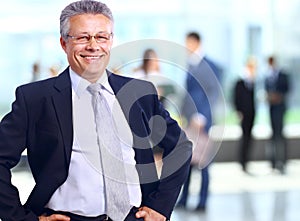 Successful business man standing with his staff in background at office