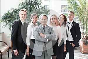 Successful business man standing with his staff in background at office