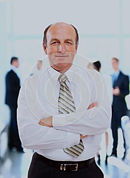 Successful business man standing with his staff in background at office.