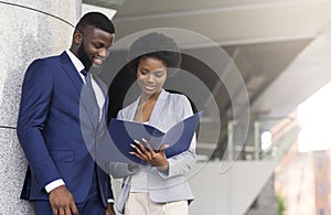 Successful business partners checking financial reports outdoors