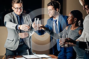 Business people clinking glasses and smiling while celebrating in meeting