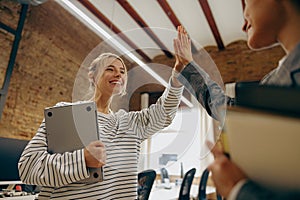 Successful business people giving each other a high five in a meeting