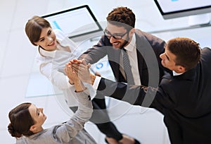 Successful business team giving each other a high-five, standing in the office