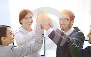 Successful business team giving each other a high-five, standing in the office