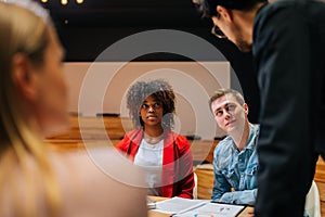 Successful business team leader standing surrounded by diverse colleagues, confidently looking to staff. Multi-ethnic