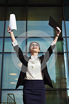 Successful business woman with arms up and documents.