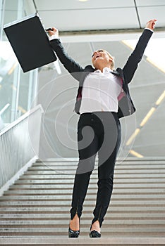 Successful business woman celebrating with arms raised