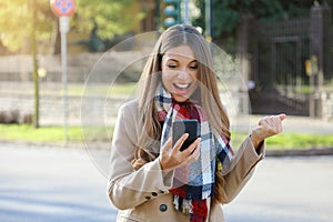 Successful business woman exults reading good news on mobile phone. Beautiful young business woman excited after achieved her photo