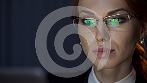 Successful business woman looking at laptop, screen reflection in eyeglasses photo