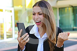 Successful business woman reading good news on smartphone and celebrate feeling happy