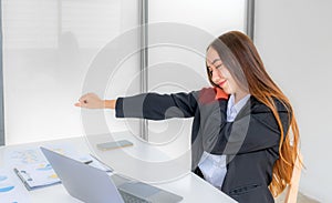 Successful business woman sitting in the meeting room Using a computer laptop to work so hard that it hurts her shoulder joint