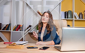 Successful business woman is sitting at the table, holding glasses in her hands