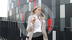 Successful business woman speaking on mobile phone in downtown businesswoman walks down street talking by mobile phone