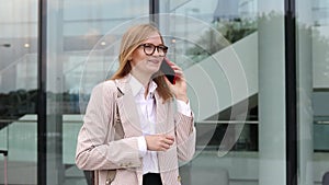 Successful business woman speaking on mobile phone in downtown businesswoman walks down street talking by mobile phone