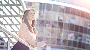 Successful business woman standing on the balcony of the modern office and looks into the distance.