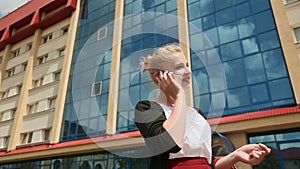 Successful business woman talking on cell phone outdoors on a background of office.