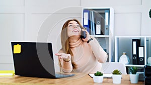 Successful business woman talking on phone in office