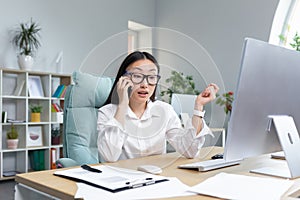 Successful business woman working in modern office, Asian woman talking on the phone, female worker wearing white shirt