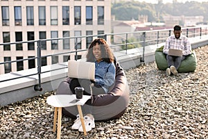 Successful business womansitting at chair bag on roof top and typing on laptop.