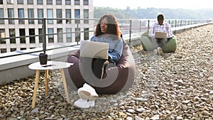 Successful business womansitting at chair bag on roof top and typing on laptop.