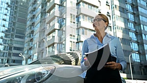 Successful businesslady holding papers in hands, smiling looking at new offices