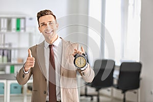 Successful businessman with alarm clock in office. Time management concept