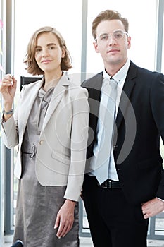 Successful businessman and businesswoman writing good ideas on sticky notes pasted on glass wall  in modern office.