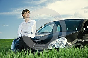 Successful businessman with car on grassland