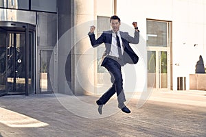 Successful businessman celebrating his victory with jump up in feeling happy on cityscape background