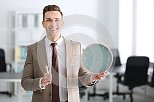 Successful businessman with clock in office. Time management concept