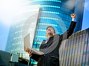 Successful businessman with computer laptop happy doing victory celebrating success