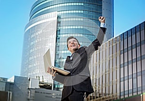 Successful businessman with computer laptop happy doing victory sign