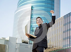 Successful businessman with computer laptop happy doing victory sign