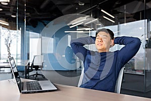 Successful businessman finished work well, Asian man put his hands behind his head and rest in the chair with closed